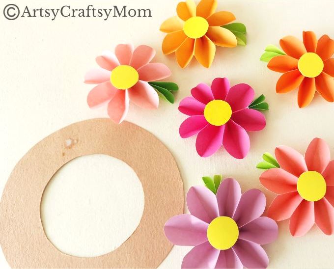 Spruce up your room or living space with this pretty paper flower wreath craft! It's easy enough for kids to make, and all you need is craft paper!