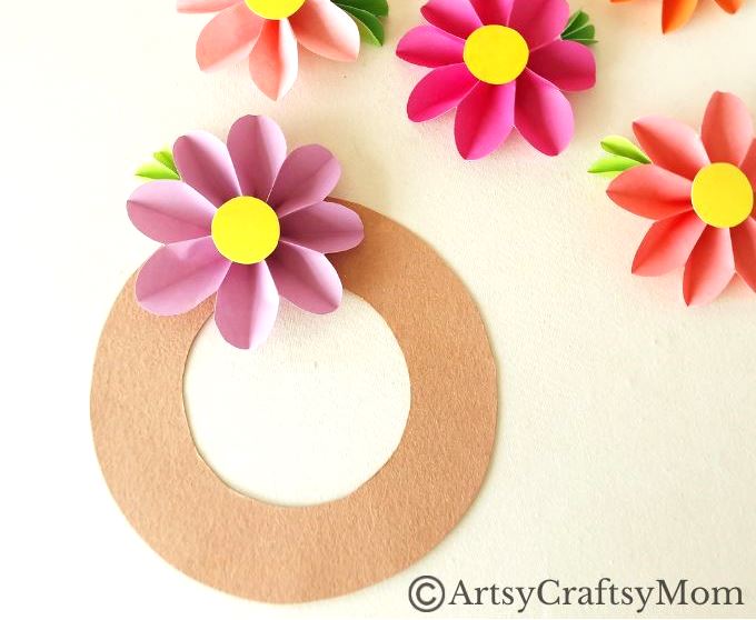 Spruce up your room or living space with this pretty paper flower wreath craft! It's easy enough for kids to make, and all you need is craft paper!