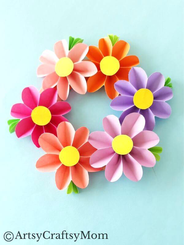 Spruce up your room or living space with this pretty paper flower wreath craft! It's easy enough for kids to make, and all you need is craft paper!